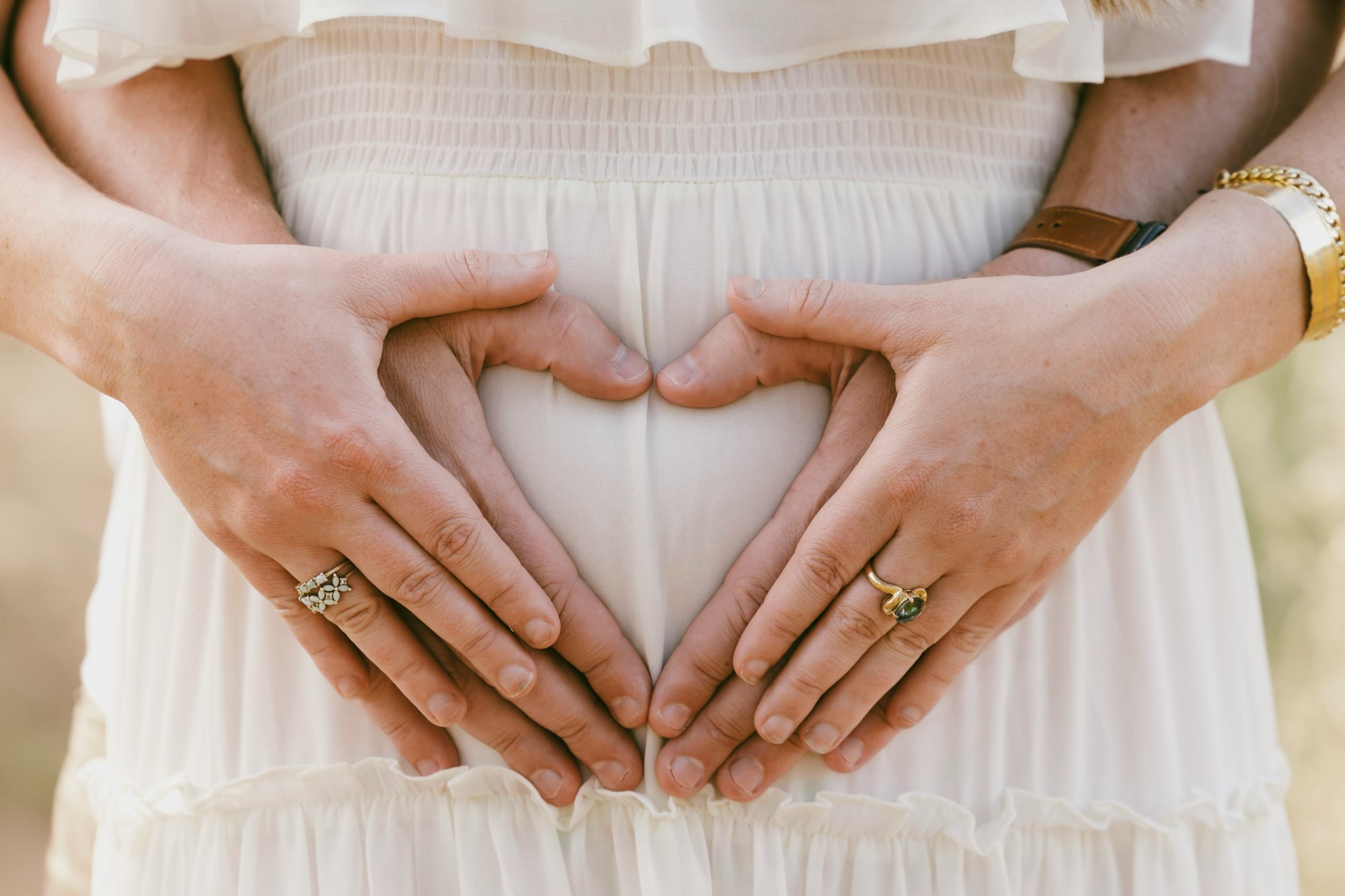 Couple forming heart on pregnant belly